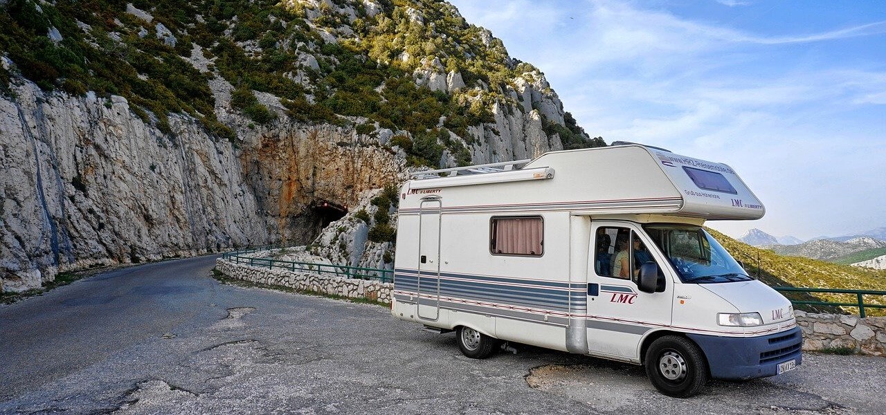 Τροχόσπιτο σταματημένο σε επαρχιακό δρόμο μπροστά από τούνελ, σε ορεινή περιοχή με καταπληκτική θέα από βουνά